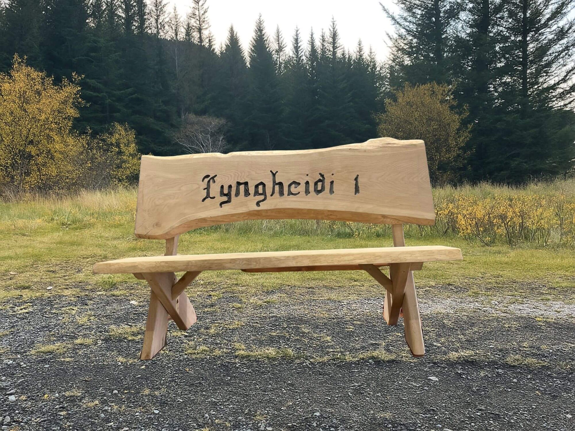Garðbekkur úr eik með áletrun „Lyngheiði“, náttúruleg hönnun sem fellur vel að íslensku landslagi.