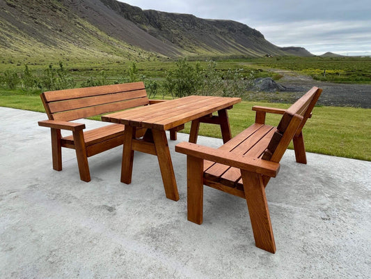 Guðrún Ósvífrsdóttir í Douglasgreni – útiborð og bekkir á steyptum palli með fjallasýn.