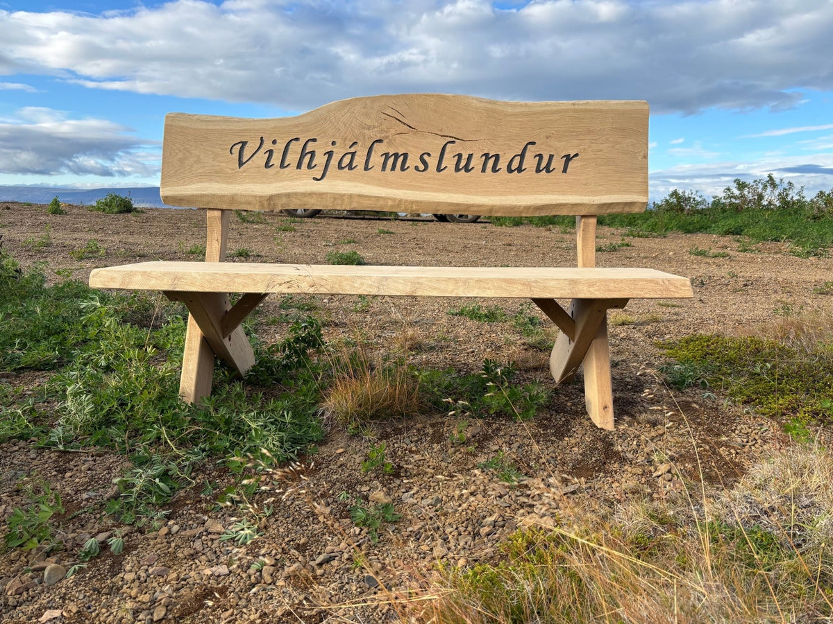 Sérmerktur garðbekkur úr eik með grafna áletrun „Vilhjálmslundur“, handsmíðaður útibekkur úr harðviði.