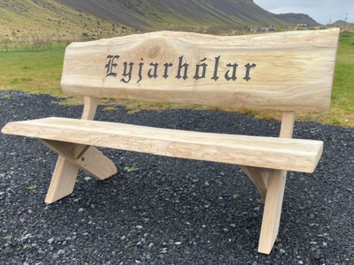 Garðbekkur úr eik með áletrun „Eyjarhólar“, náttúruleg hönnun sem fellur vel að íslensku landslagi.
