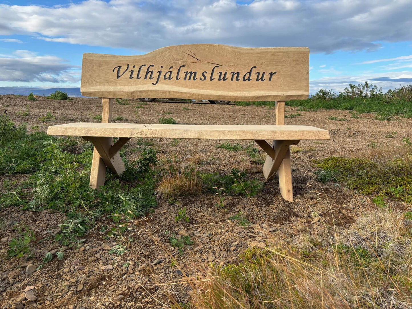Sérmerktur garðbekkur úr eik með grafna áletrun „Vilhjálmslundur“, handsmíðaður útibekkur úr harðviði.